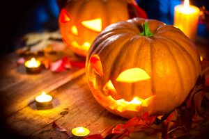 Halloween pumpkin head jack lantern with burning candles over wo